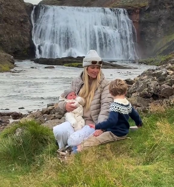 A woman with two young children sitting by a waterfall.