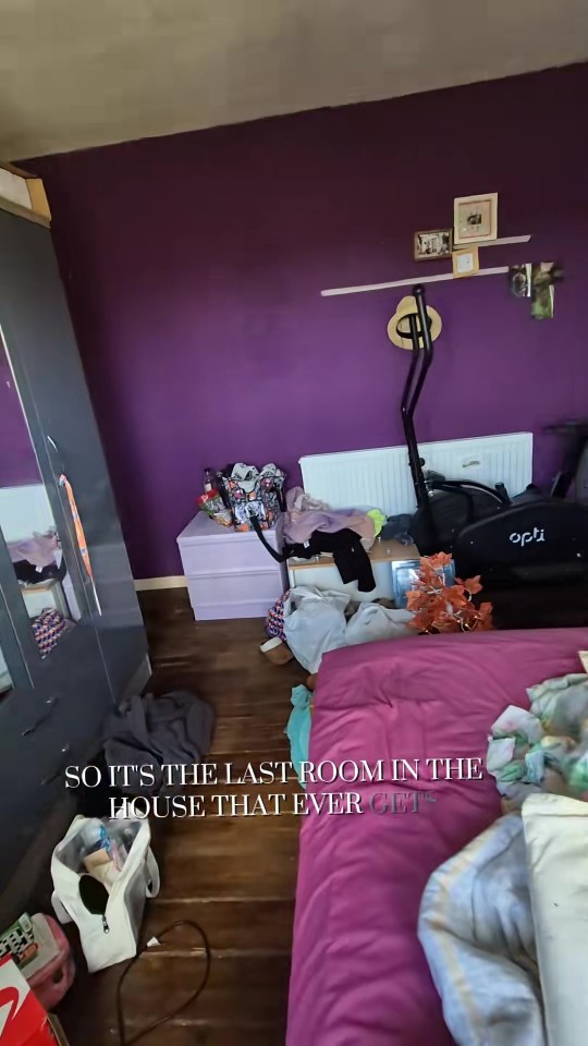 Messy bedroom with purple walls, a pink bed, and exercise equipment.