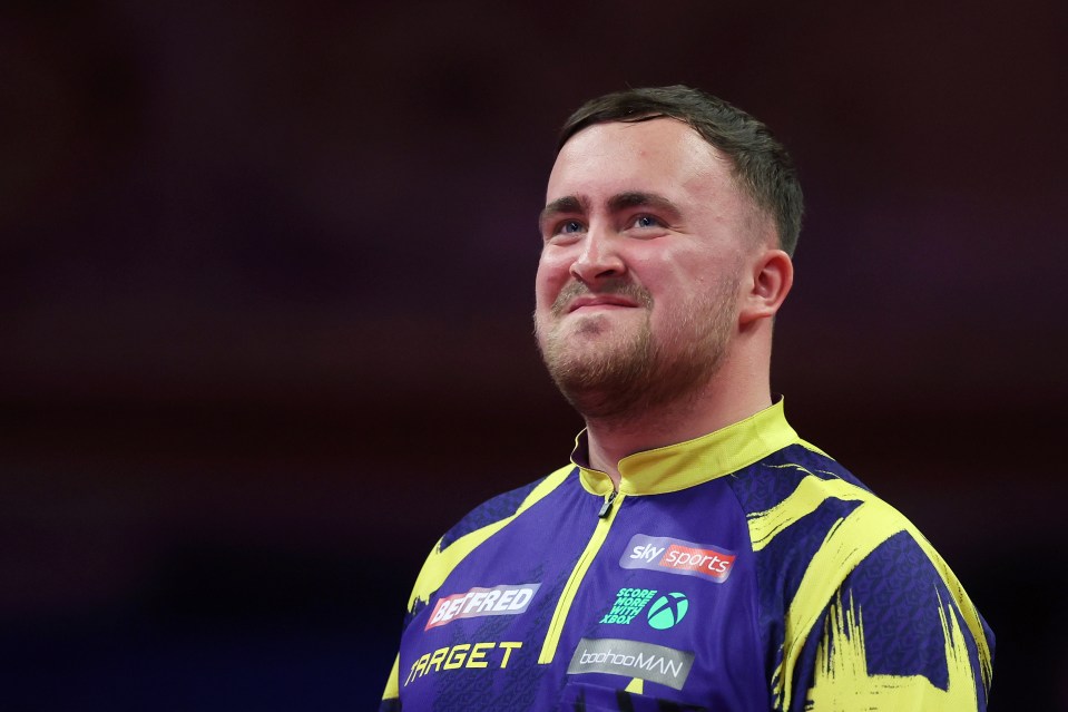 Luke Littler of England smiles during a dart match.
