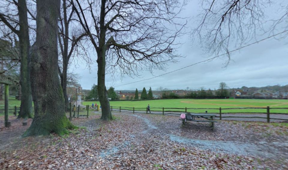 Clair Park with a person walking along a fence next to a field.