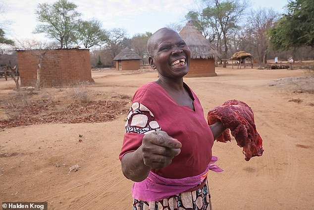 Estanaty, 60, stands in front of her home with a gifted handful of the elephant meat