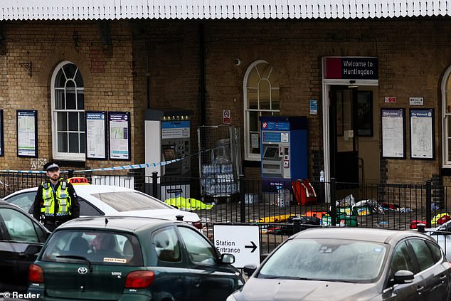 A police officer stands guard at Huntingdon Station this morning where people's belongings lay scattered on the ground