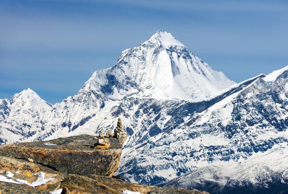 Snow-capped Dhaulagiri mountains with stone pyramids in the foreground.