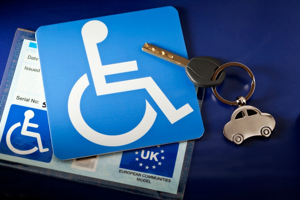 A UK handicapped parking permit (Blue Badge) with a car key and car-shaped keyring.