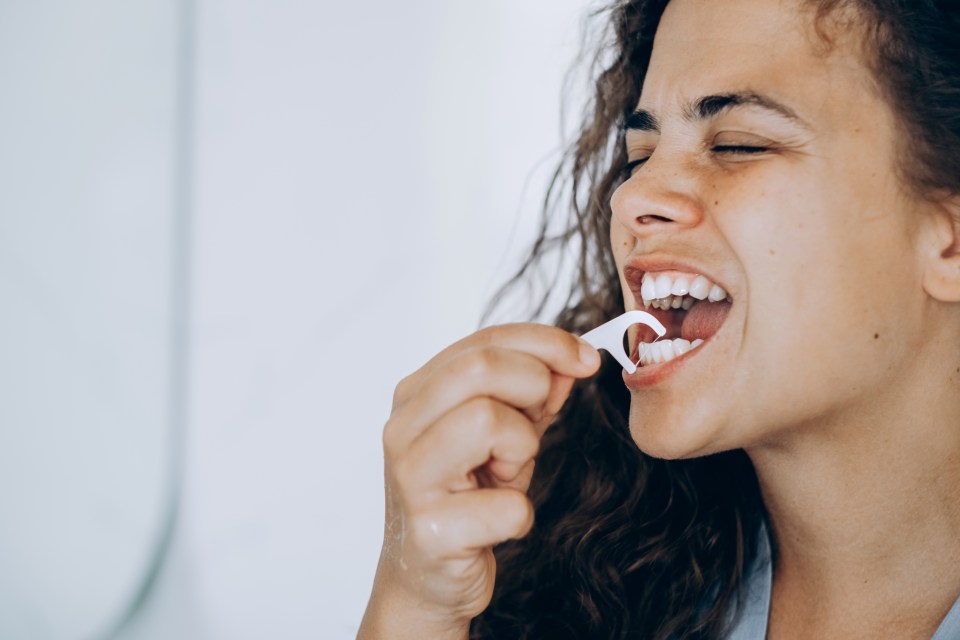 Young brunette woman flossing her teeth. Beautiful smile. Dental health and beauty.