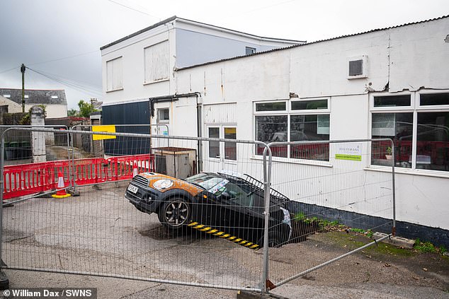 Authorities are also questioning how to free the car before it falls deeper into the sinkhole, and doing it in a way that won't cause more of the earth to collapse with it