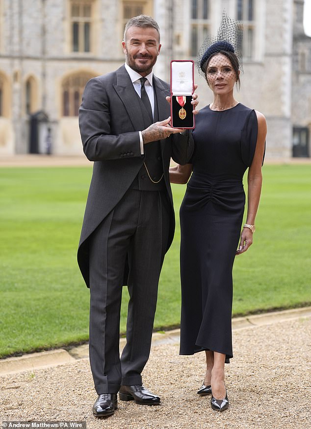 A proud Sir David shows off his medal in the grounds of Windsor Castle while accompanied by wife Victoria, who designed and made his suit as a gift