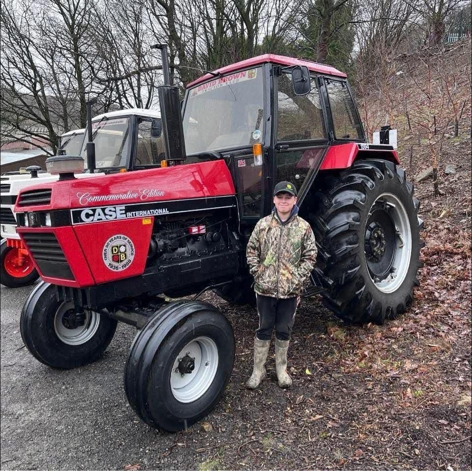 Jack David Allott standing next to a red Case International tractor.