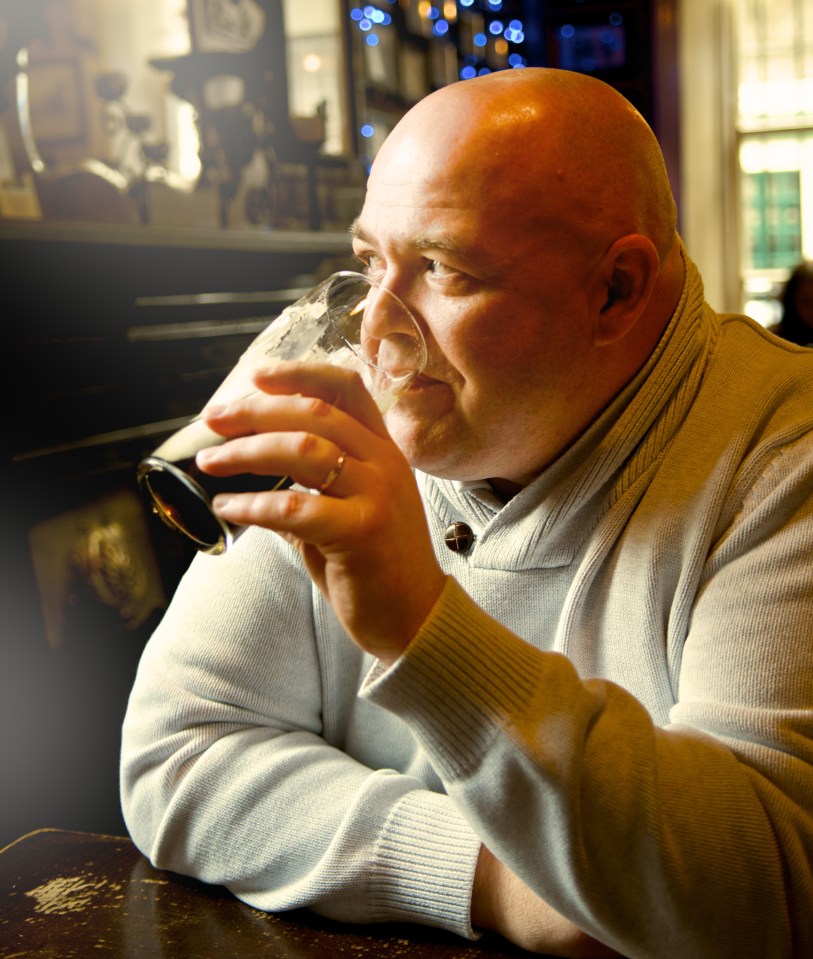 Bald man drinking a pint of stout beer in a pub.