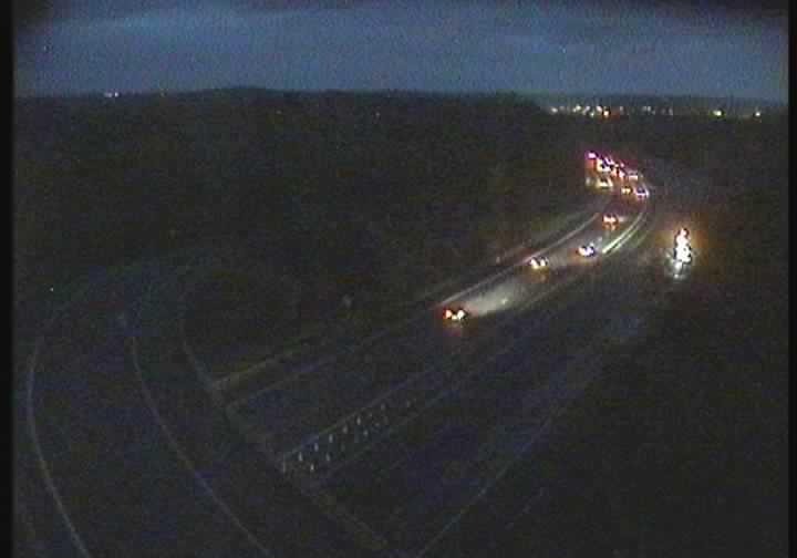 A night-time view of traffic on a multi-lane highway, with vehicles visible by their headlights and tail lights.