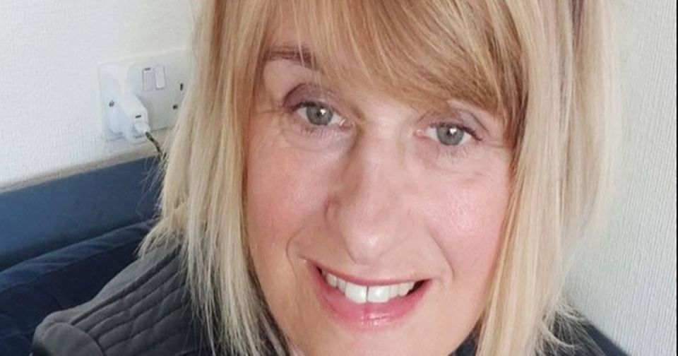 Portrait of a smiling woman with blonde hair, gray eyes, and fair skin.