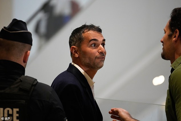 Defendant Aurelien Poirson-Atlan, centre, arrives at the courtroom as ten people go on trial over cyberbullying of Brigitte Macron