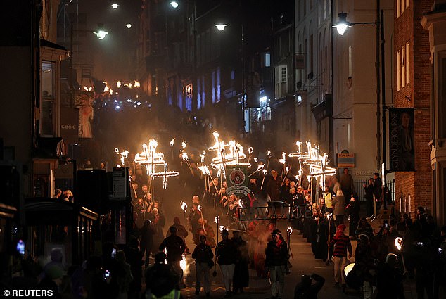 Participants bearing torches march through the town of Lewes, holding aloft flaming crosses