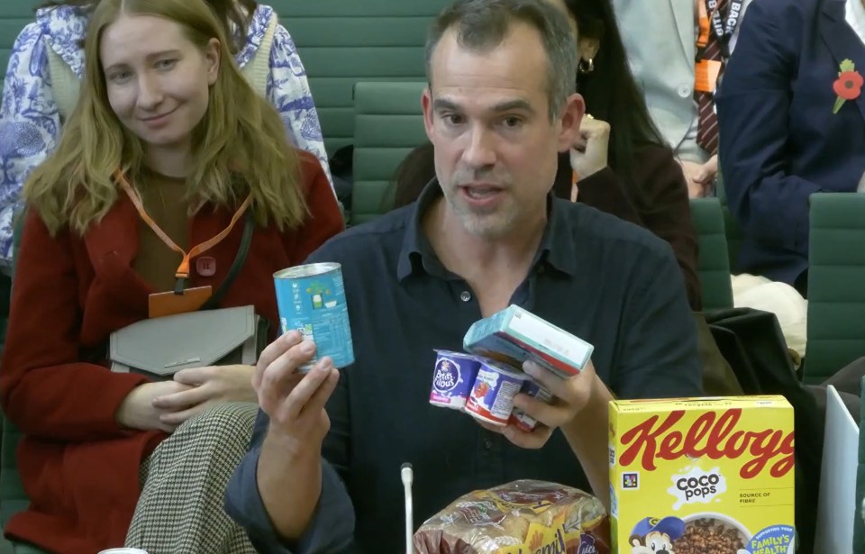 Chris van Tulleken holding a blue can, yogurt pots, and a box of Coco Pops.
