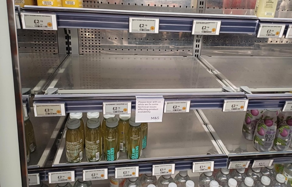 Empty shelves inside a Marks & Spencer shop with a sign citing "technical issues affecting product availability."