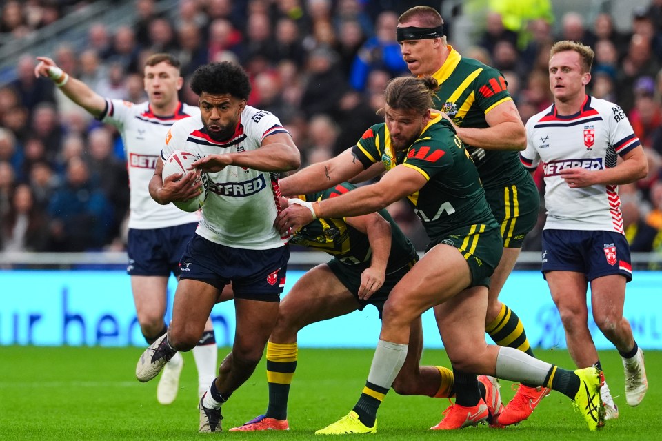 England player Watkins evades a tackle from Australian players in a Rugby League Ashes match.