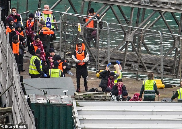 Small boat migrants disembark from a Border Force vessel at Dover earlier