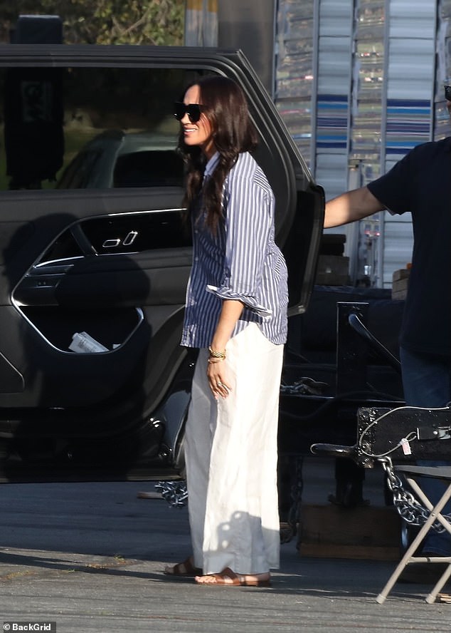 She was seen wearing a casual white and navy pinstripe shirt, which she paired with an elegant white linen maxi skirt