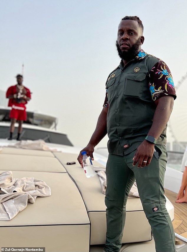In a picture purportedly from Dubai in 2022, Zül-Qarna¿n Nantambu is seen standing on a yacht. As he told Daily Mail, it's Antonio Brown who is pictured wearing red in the background
