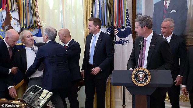 The man (second from left) is captured as he begins to faint in the Oval Office Thursday in the middle of the President's announcement on drug pricing