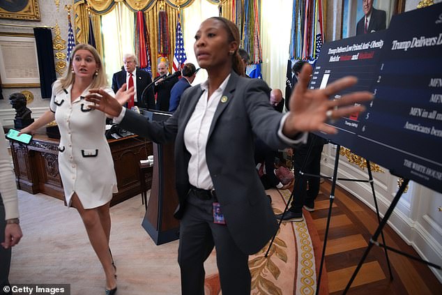 A White House aide (left) and a member of the Secret Service (center) usher members of the media out of the Oval Office after the guest collapsed