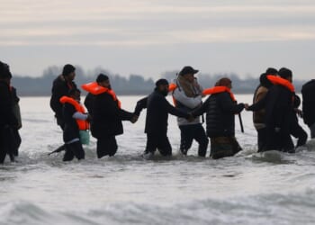 Migrants join hands making way to small boat which eventually collapsed in the Channel en route to UK