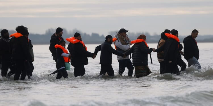 Migrants join hands making way to small boat which eventually collapsed in the Channel en route to UK