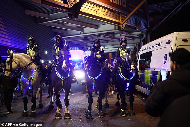Police officers on horses attempt to keep the crowd under control ahead of the fixture