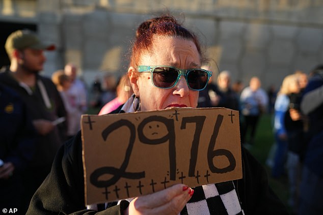Karen Yount holds a sign reading '2976' during a vigil Thursday