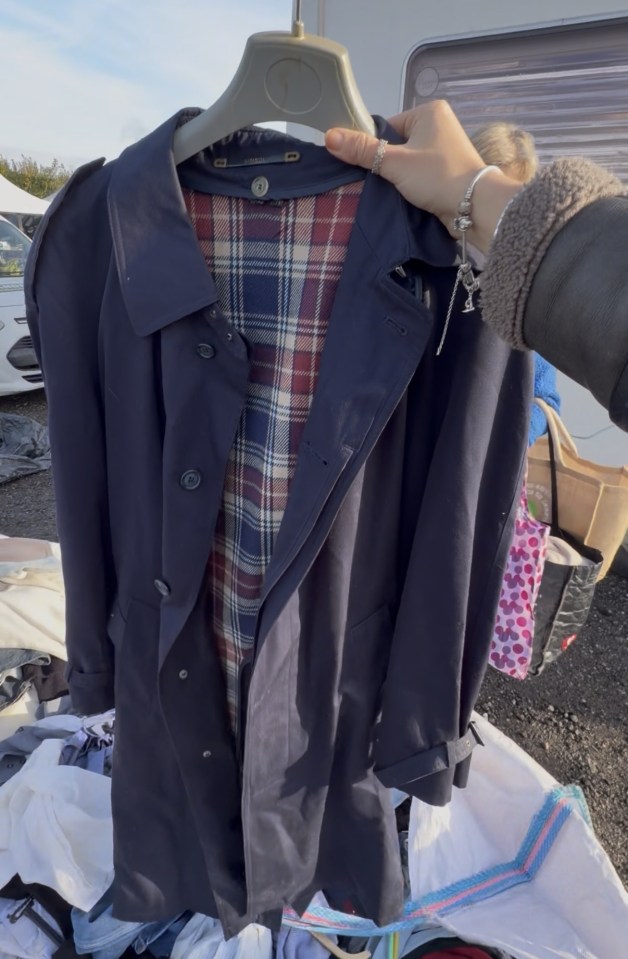 Navy Baracuta trench coat with a red, white, and blue plaid lining, held up by a person at a car boot sale.