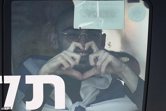 Rom Braslavski smiles making a heart sign from a minibus at the Sheba Medical Center in Ramat Gan, Israel, Monday, Oct. 13, 2025