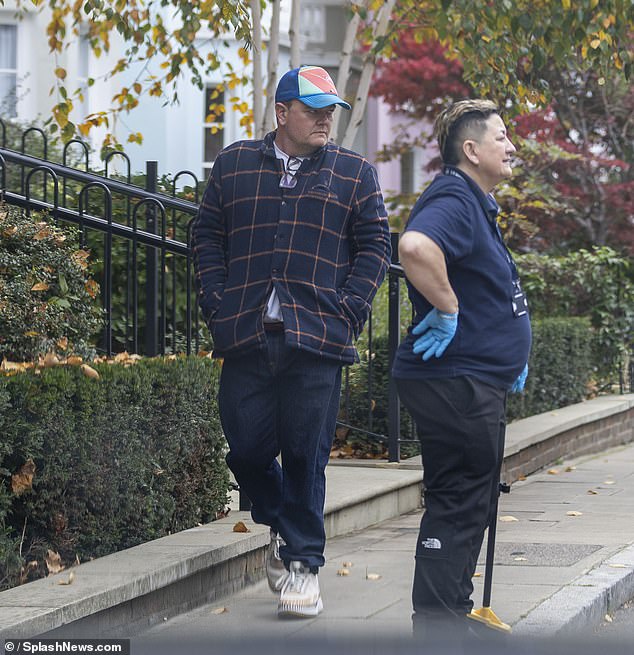 Snapped in London, the comic wore a multicolored Urban Outfitters cap and a navy Timberland jacket with an orange check pattern, paired with jeans and casual sneakers