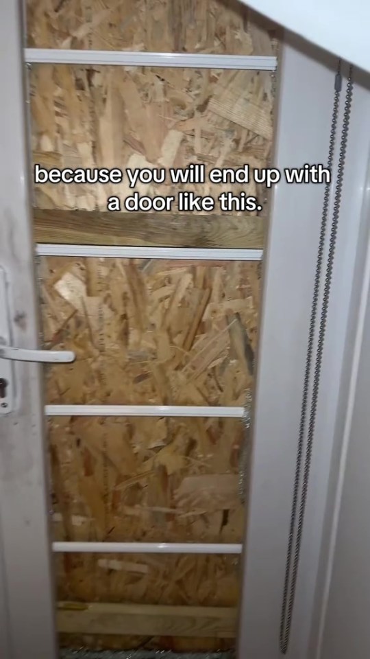 A boarded-up door with visible broken glass on the floor.