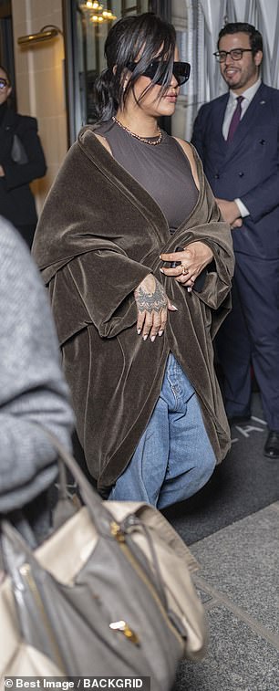 Legendary singer Rihanna rocked a brown coat and denim and shielded behind a pair of oversized shades
