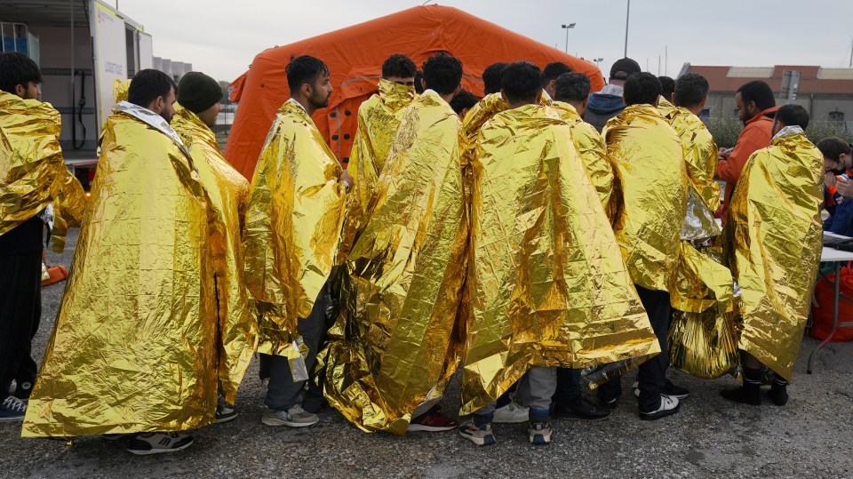 Migrants rescued from a collapsed boat in the Channel from France are wrapped in gold thermal blankets in Dunkirk.