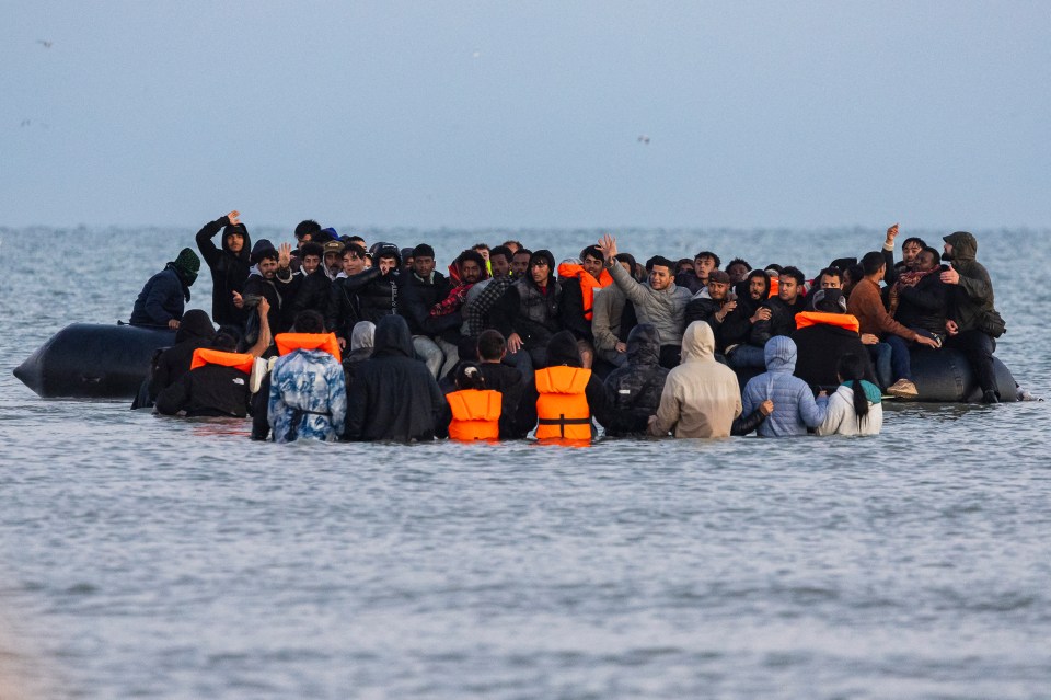 Migrants trying to board a crowded smuggler's boat to cross the English Channel.