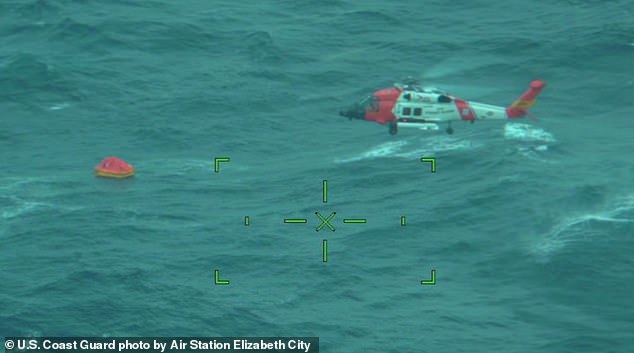 Photos released by the Coast Guard capture a Jayhawk helicopter hovering over stormy Atlantic waters, with a small orange raft tossed by waves and wind nearby (pictured)