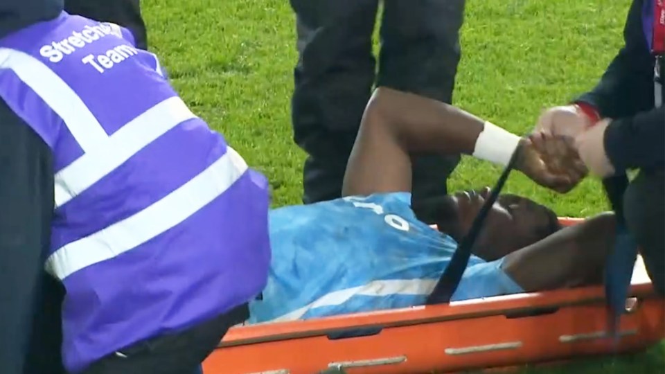 A soccer player on a stretcher being attended to by medical staff.