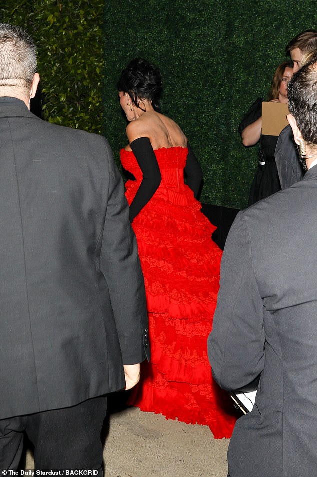 She made her way into the starry bash in a bright red, strapless gown with ruffled tiers cascading into a train, trailing behind her. She paired the eye-catching dress with long, black opera gloves and styled her hair into a pinned updo as she made her way into the party