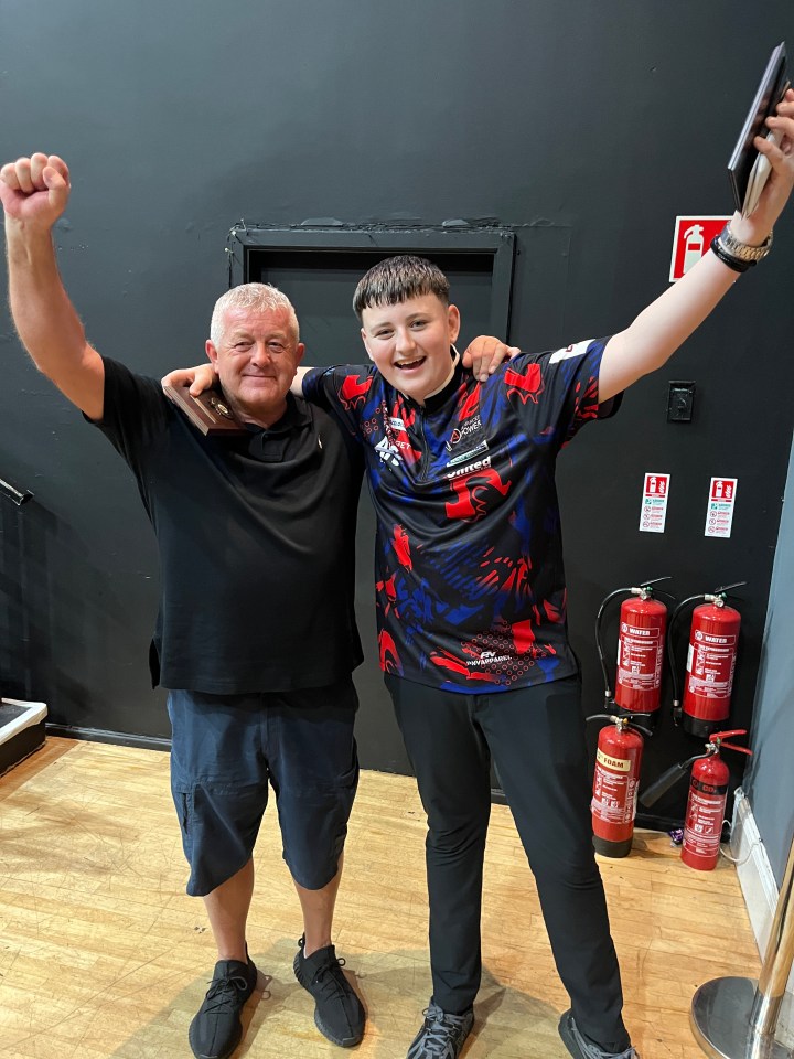 Mitchell and his grandad Dougie raising their arms in celebration, with Dougie holding a trophy.