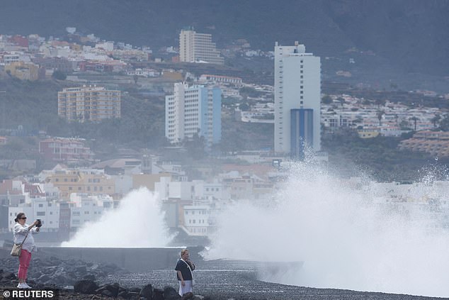 A tourist takes a photo of her daughter with large waves in the background during the alert for poor sea conditions in the Canary Islands, Puerto De La Cruz, Spain, March 26, 2024