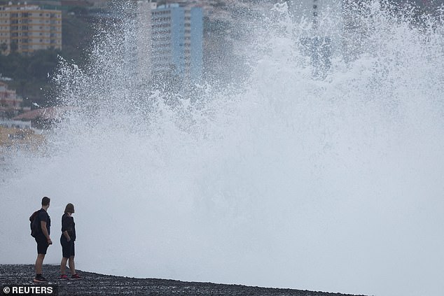 Tourists react to a large wave in Puerto De La Cruz, during the alert for bad sea conditions in the Canary Islands. Spain, March 26, 2024