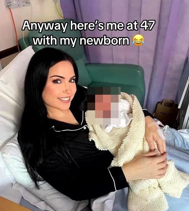 A 47-year-old mother holding her newborn baby in a hospital bed.