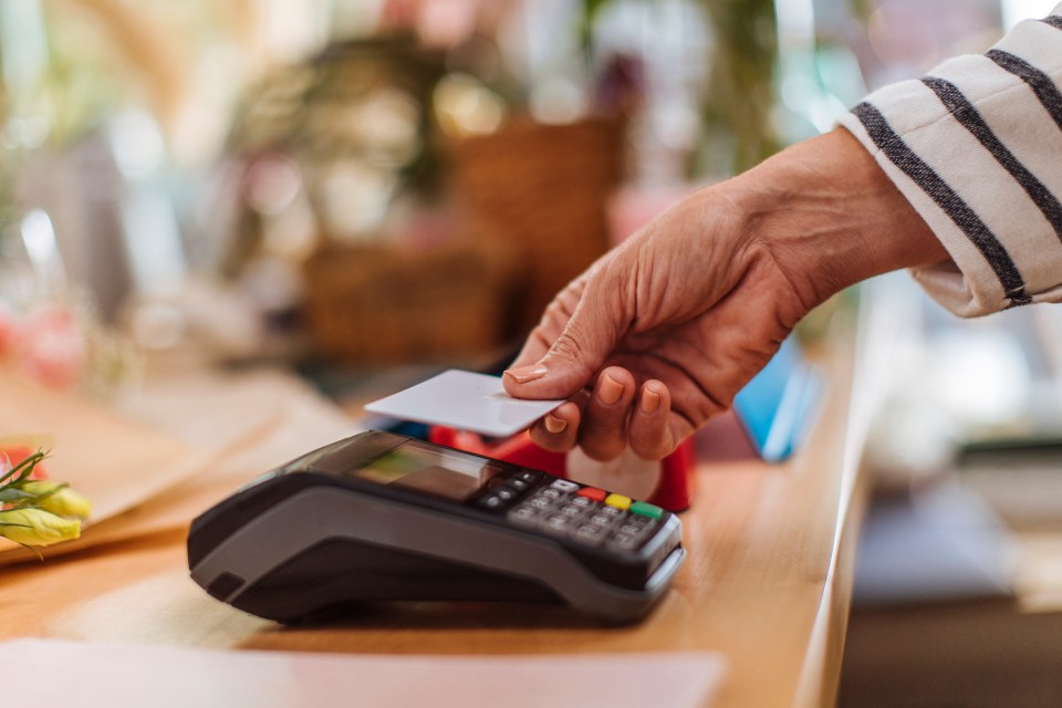 Person making a contactless credit card payment at a flower shop.