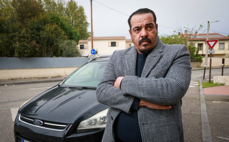 Nasim Mimun, a private hire driver, stands in front of his black Ford car.