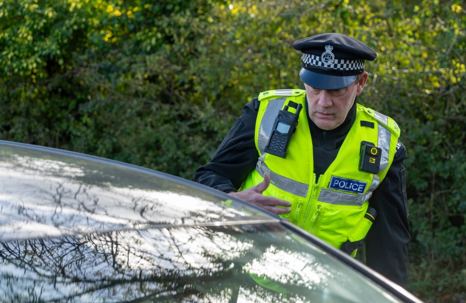 UK police officer approaching a parked car.