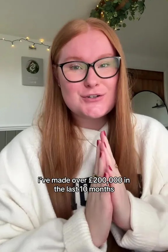 A young woman with red hair and glasses, wearing a white sweatshirt, speaks while holding her hands together in front of her chest. Text overlay says, "i've made over £200,000 in the last 10 months."