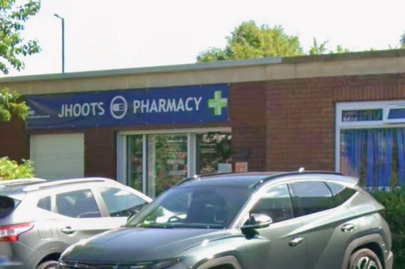 Jhoots Pharmacy building with cars parked in front.