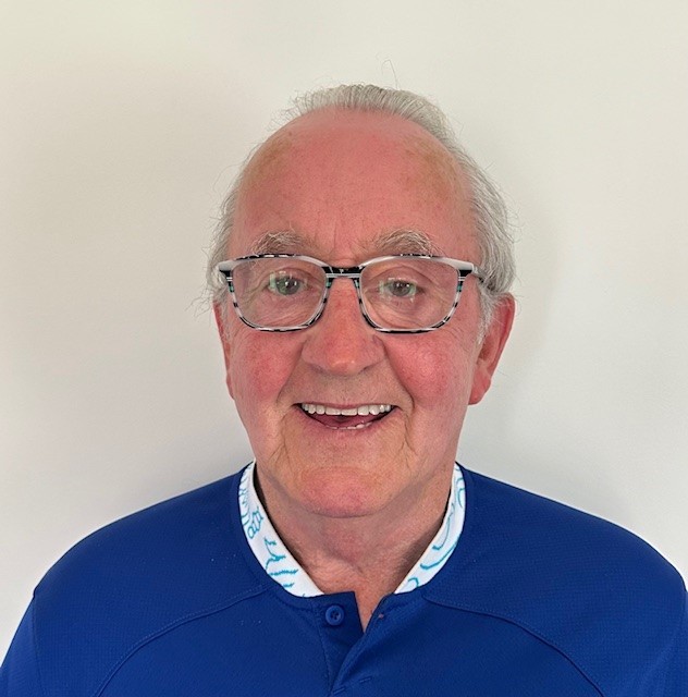 John Gerard Boyle smiling while wearing glasses and a blue shirt.