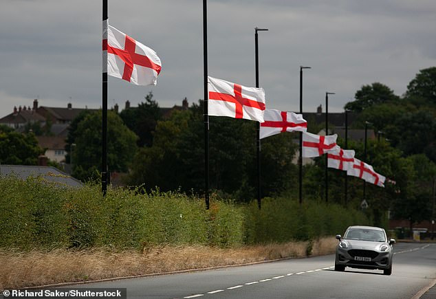 Cars drive past St George flags on lampposts in Bartley Green, a suburban district in south west Birmingham